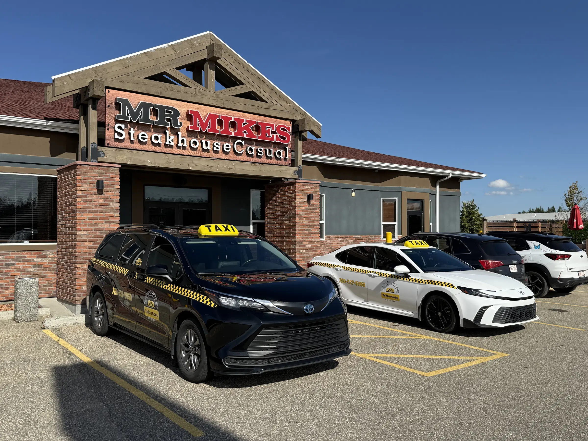 Yellow Cabs Whitecourt fleet of taxis parked outside a local restaurant
